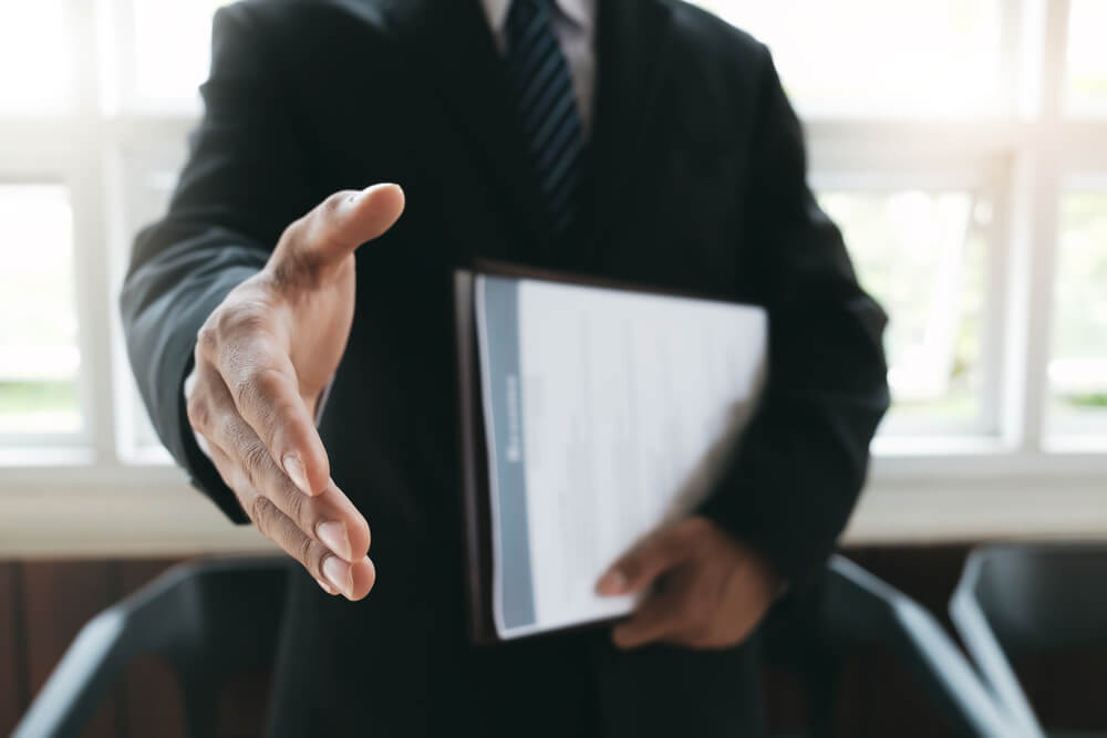 advogado estendendo a mão após acordo referente à aposentadoria por tempo de contribuição