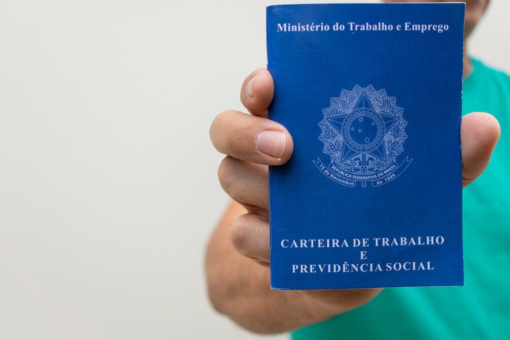 pessoa segurando uma carteira de trabalho, representando a tabela do salário mínimo para os trabalhadores