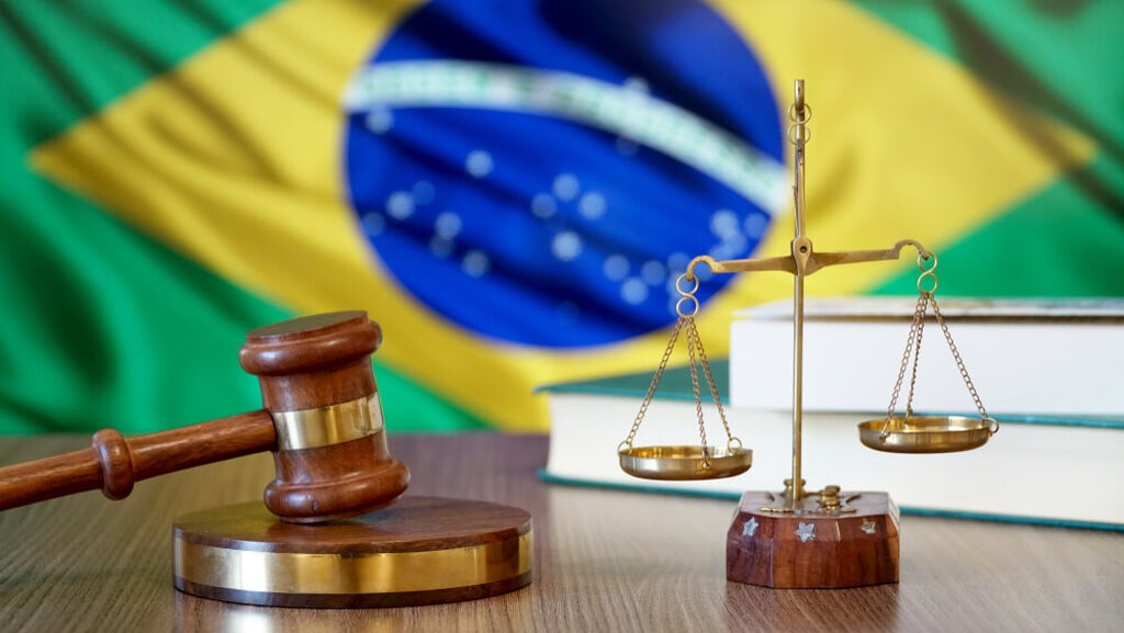 martelo de juiz e balança em frente à bandeira do Brasil, representando o limbo previdenciário
