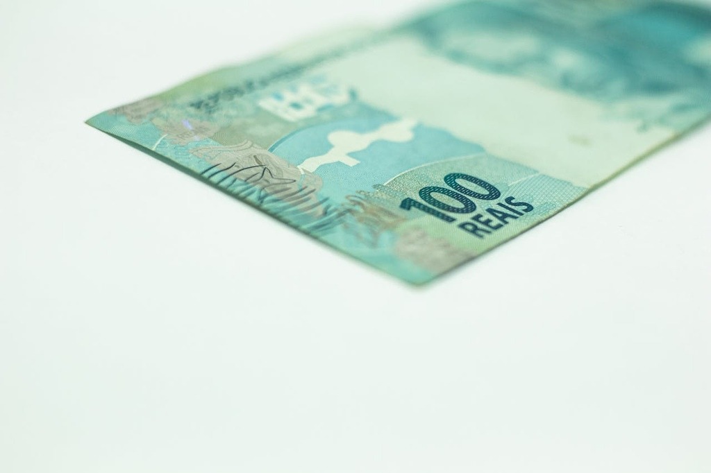 nota de 100 reais representando se é possível receber pensão por morte e aposentadoria