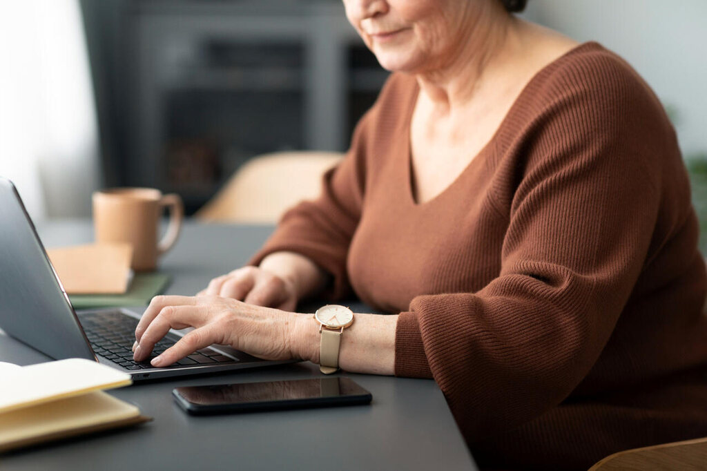 Mulher fazendo consulta online pelo notebook sobre regras do INSS para entrada na aposentadoria faltando um mês.