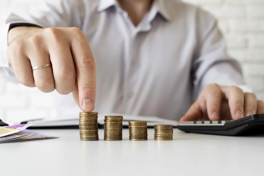 homem fazendo escadinha de moedas representando a distribuição do salário de contribuição