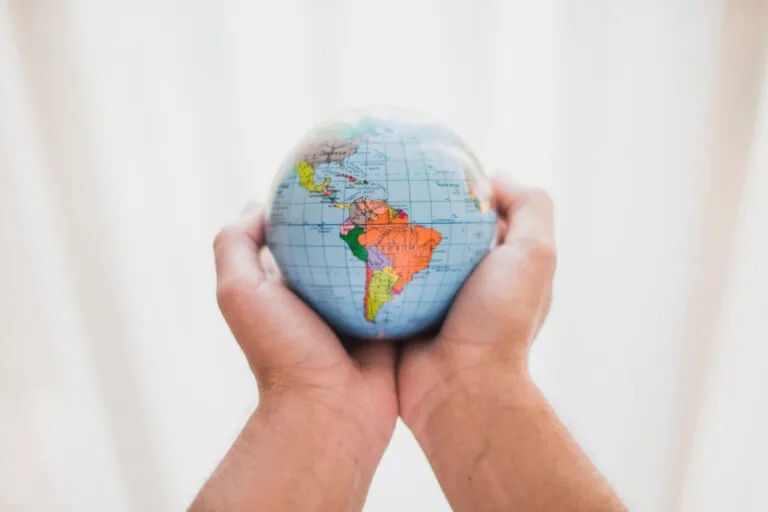 mãos segurando globo representando o Acordo Internacional no INSS