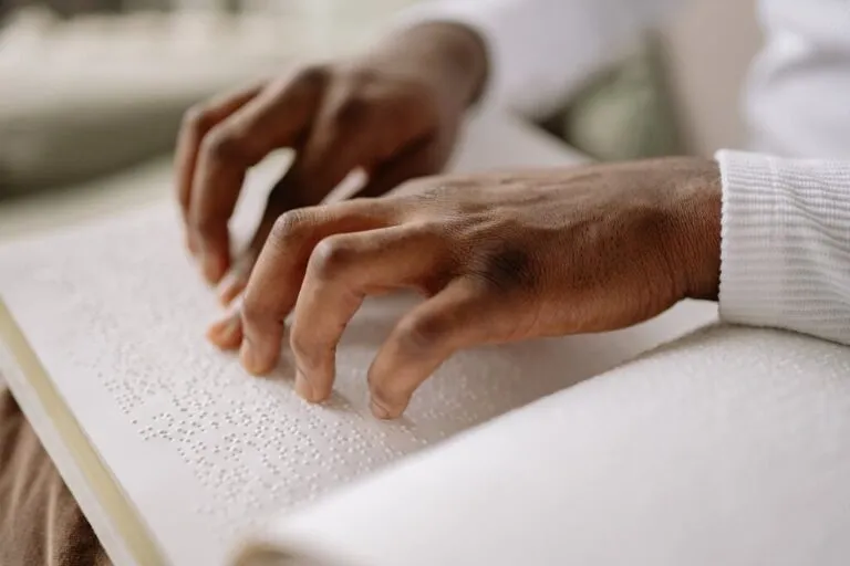 mãos de pessoa com deficiência visual fazendo leitura de livro em braile, representando quanto tempo dura o BPC/Loas