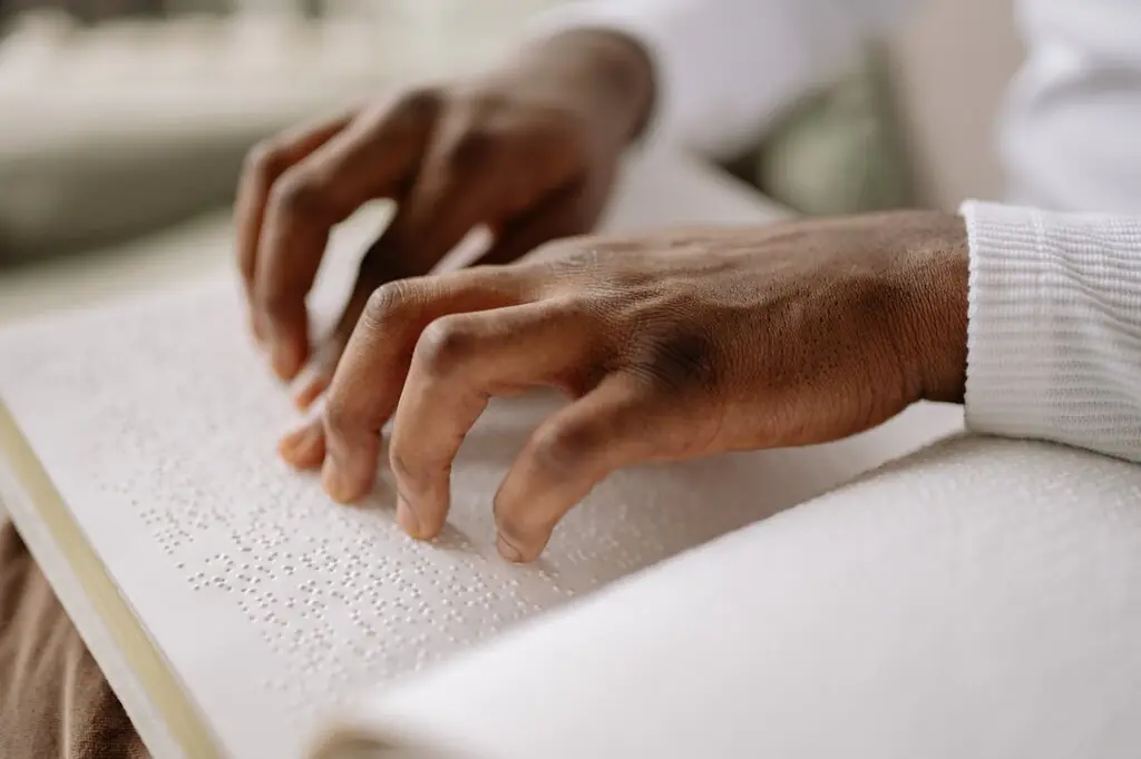 mãos de pessoa com deficiência visual fazendo leitura de livro em braile, representando quanto tempo dura o BPC/Loas